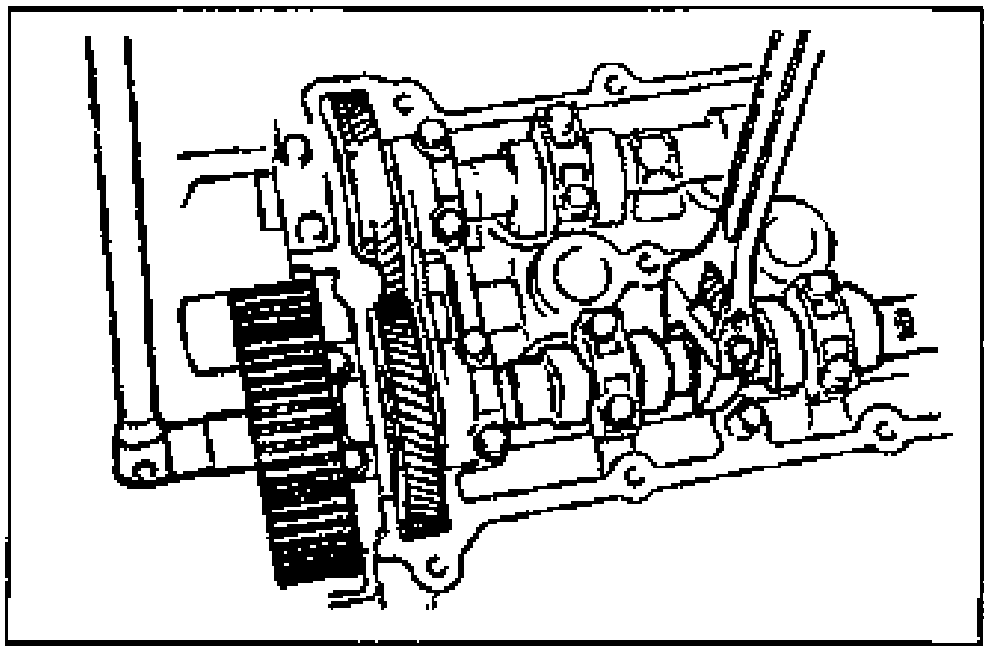 View of holding the camshaft with a wrench on the cast hexagon while tightening the camshaft pulley lock bolts; camshaft and pulley teeth visible.