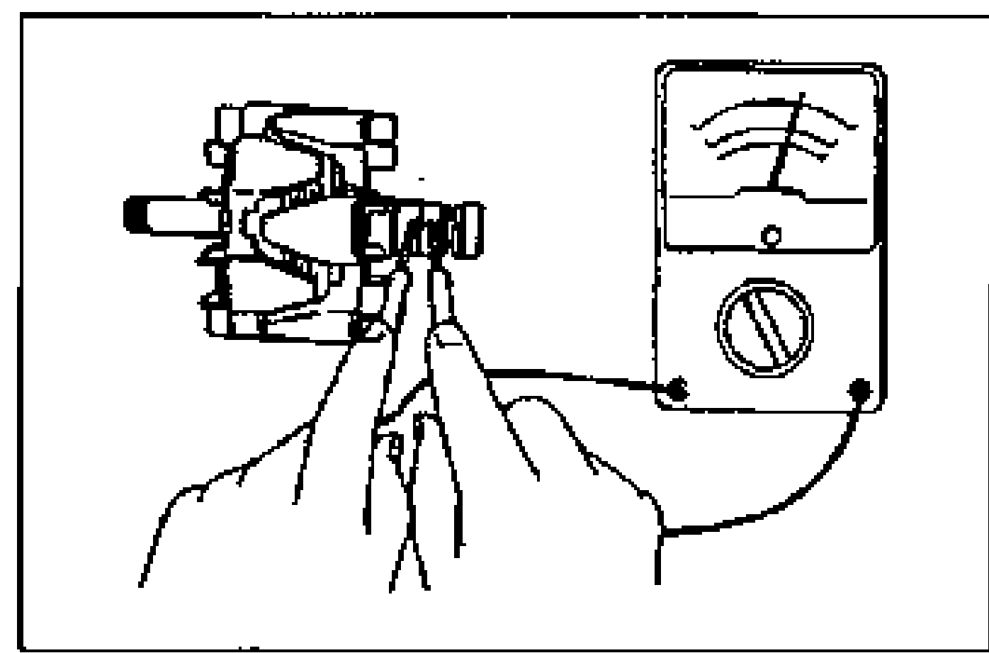 Hand holding the alternator rotor with an ohmmeter probing between the two slip rings to check continuity.