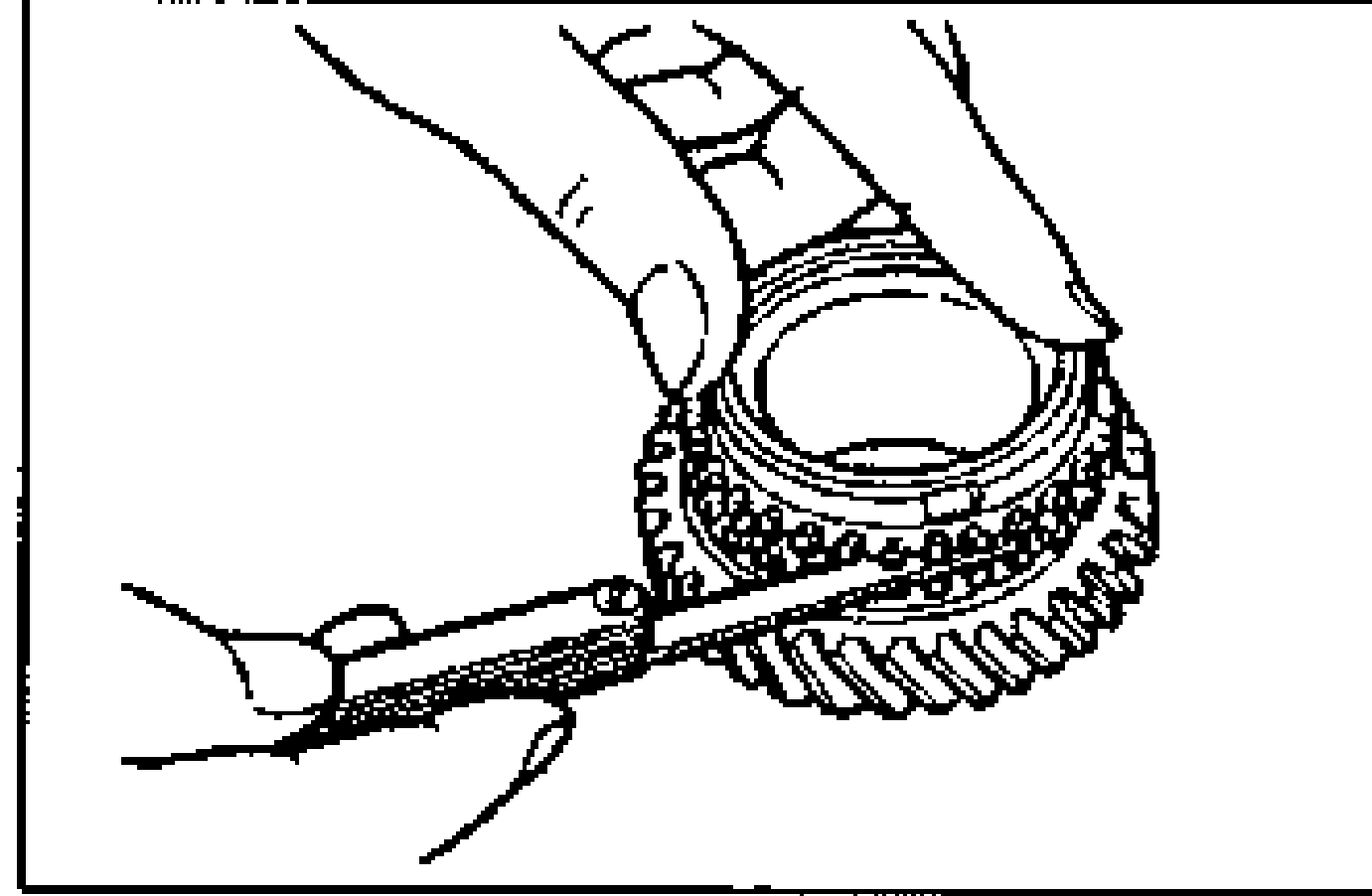 Line drawing of a hand using a feeler gauge to measure the clearance between the synchronizer ring set squarely in the gear and the flank surface of the gear.