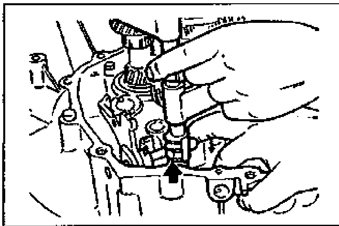 Photo of a hand tapping the shift rod from above with the clutch hub sleeves set to neutral; an arrow points down at the shift rod so the steel ball drops into the center groove of the control end.