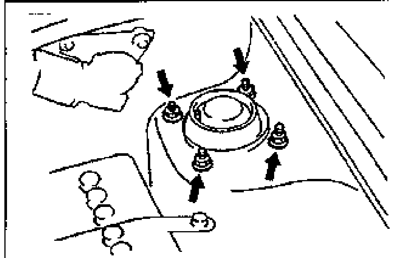 Top view of the front strut mounting block in the engine bay with four downward arrows pointing to the mounting block nuts to be removed.